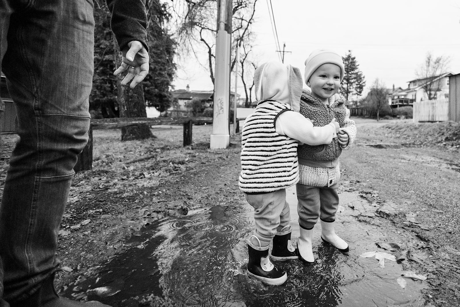 Two young children playing in a puddle while having candid family photographs taken by Sea to Sky Studios in Vancouver.